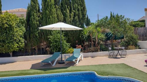 a patio with two chairs and an umbrella next to a pool at La Casa Arboleas in Arboleas