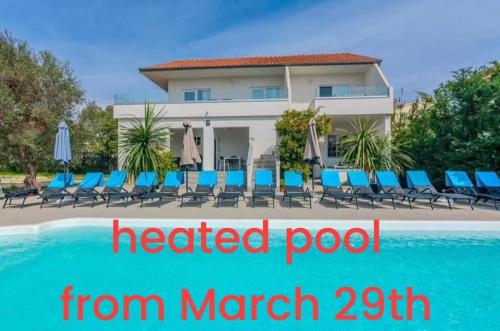 a hotel with a heated pool with chairs and umbrellas at ROYAL CHOICE WITH POOL in Zadar