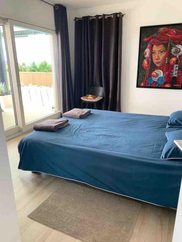 a bedroom with a large blue bed with a window at Appart avec piscine chauffée et plage 5 min in Perroy