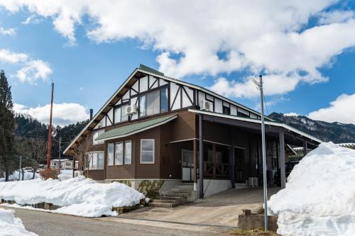 a house with snow piled up around it at Cottage Roots コテージルーツ in Hida