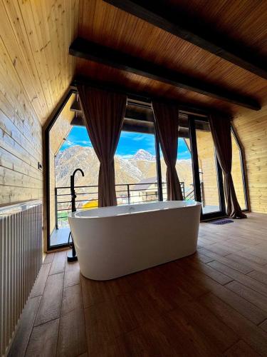 a bath tub in a room with a large window at Chill inn kazbegi in Stepantsminda