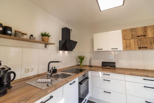 a kitchen with white cabinets and a sink at Ferienhaus Klötzlehuus in Krummhörn