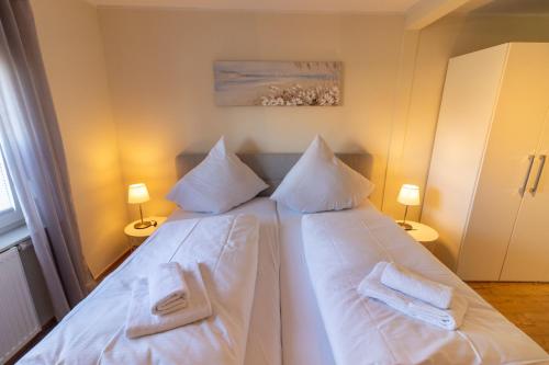 a bedroom with a white bed with two towels on it at Ferienhaus Klötzlehuus in Krummhörn