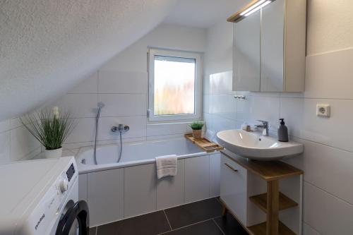 a white bathroom with a sink and a bath tub at Ferienhaus Klötzlehuus in Krummhörn