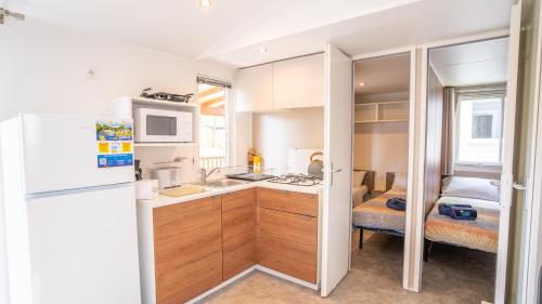 a small kitchen with a refrigerator and a sink at Happy Camp Mobile Homes in Valamar Camping Lanterna in Poreč