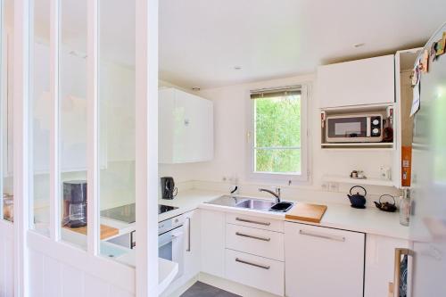 une cuisine blanche avec un évier et un micro-ondes dans l'établissement House for 8 people, 5 min by bus to Disneyland, à Serris
