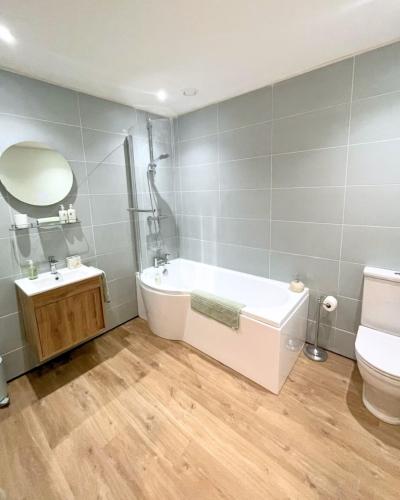 a bathroom with a tub and a toilet and a sink at Estuary's Rest Studio Apartment at Galwad Y Mor in Cardigan