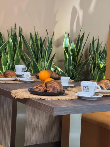 Ein Tisch mit Croissants, Orangen und Tassen Kaffee in der Unterkunft Di Prima Albergo Diffuso in Catania
