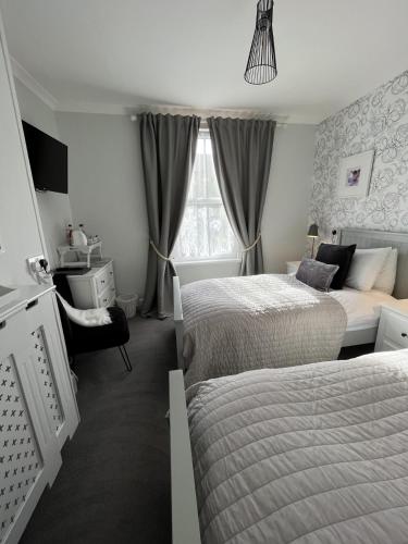 a bedroom with two beds and a couch and a window at The Glastonbury Townhouse B&B in Glastonbury