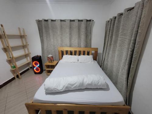 a bedroom with a wooden bed with white sheets at EMMY'S HIDE AWAY in Iringa
