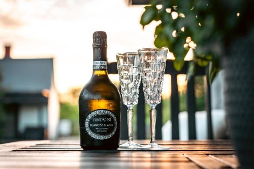 a bottle of wine and two glasses on a table at Saarelux Riverise Villa in Mõraste