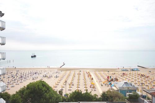 a beach with chairs and umbrellas and the ocean at Hotel Terramare in Lido di Jesolo