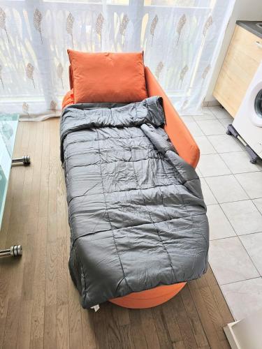 - un canapé orange avec un oreiller orange dans l'établissement Agréable 2 pièces proche du métro, à Villejuif