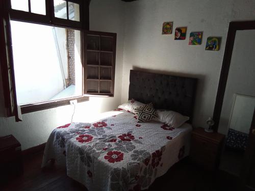 a bedroom with a bed with a flowered blanket and a window at Casa Argot in Santiago