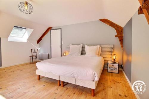 a bedroom with a large white bed with wooden floors at Domaine de lafayette - sejours bien-etre et detente in Saint-Marcel