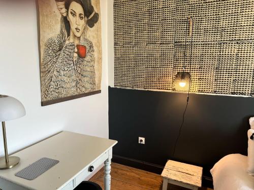 ein Zimmer mit einem Tisch und einem Bild einer Frau mit einer Tasse in der Unterkunft Villa Marguerite - Chambres d'Hôtes in Saint-Omer