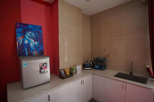 a kitchen with a refrigerator and a painting on the wall at Love Hotel - Khách Sạn Theo Giờ in Da Lat