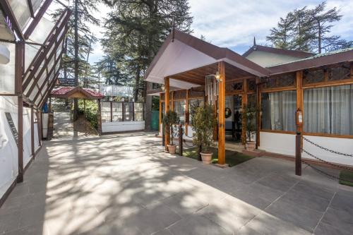 a house with a porch with trees in the background at Treebo Premium Torrentium - A Heritage Hotel in Shimla