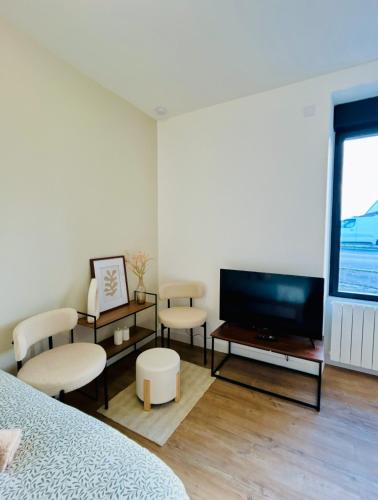 - une chambre avec une télévision à écran plat et des chaises dans l'établissement Mini Studio Tout confort - accès facile Nantes et Vendée, à Pont-Saint-Martin