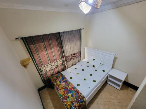 a small bedroom with a white bed and a chair at EMMY'S HIDE AWAY in Iringa