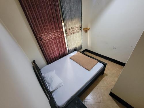 a small bed in a small room with a window at EMMY'S HIDE AWAY in Iringa