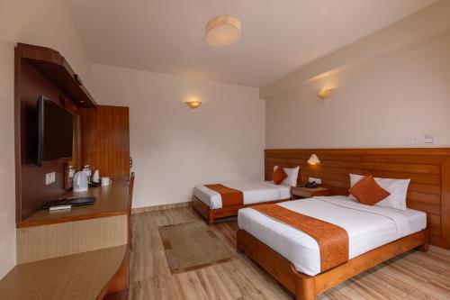a hotel room with two beds and a television at Mount View Pokhara in Pokhara