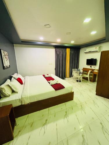 a bedroom with a bed and a desk and a television at The Elite Beachview in Puducherry