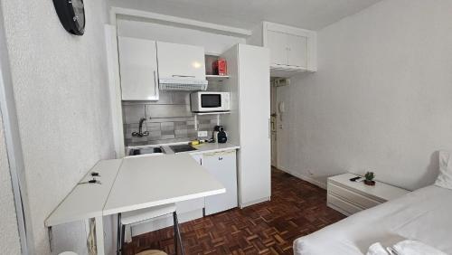 a small kitchen with white cabinets and a white table at Estudio en Gran Via centro in Madrid