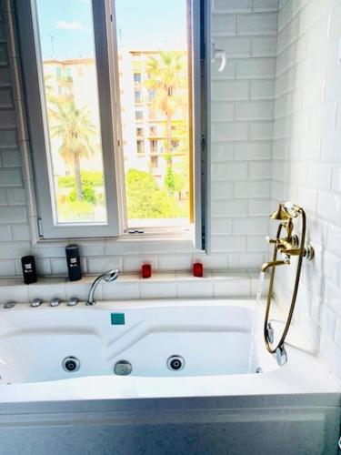 La salle de bains est pourvue d'une baignoire blanche et d'une fenêtre. dans l'établissement Spacious Appartment 5 min to sea, à Nice