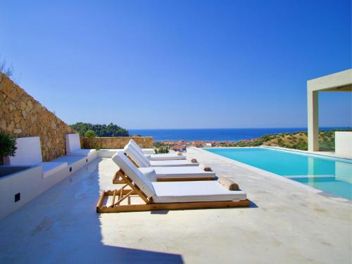 eine Reihe von Liegestühlen am Rand eines Swimmingpools in der Unterkunft Design Villa Nea Skioni by Halkidiki Villas in Nea Skioni