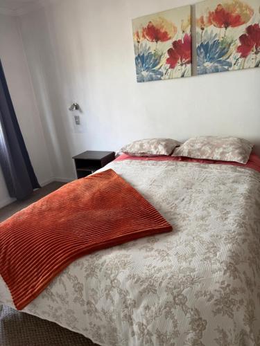 a bed with two pillows and an orange blanket on it at Apartamentos altos del centro Freire in Osorno