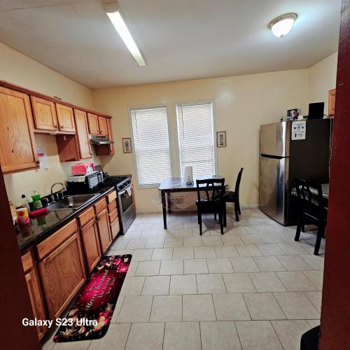 a kitchen with a refrigerator and a table with chairs at Divine Villa & Resorts Guest House - 283 Lehigh Ave in Newark