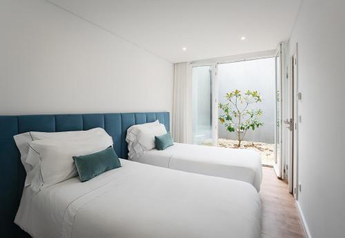 two beds in a room with a window at Feel Porto Lapa Collection Flats in Porto