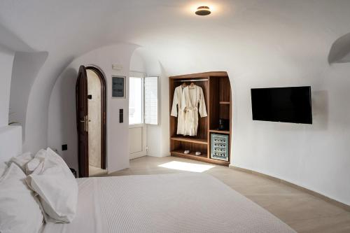 a bedroom with a bed and a tv in a room at Enalion Suites in Oia