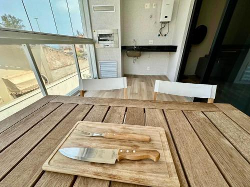 a wooden cutting board with a knife on a table at Praia de Piratininga Apartamento Vista Para o Mar in Niterói