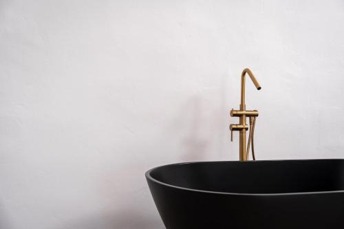 a black bath tub with a brass faucet at Enalion Suites in Oia