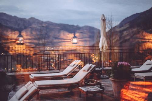 a group of lounge chairs on a balcony with mountains at Alpine Spa Hotel Haus Hirt in Bad Gastein