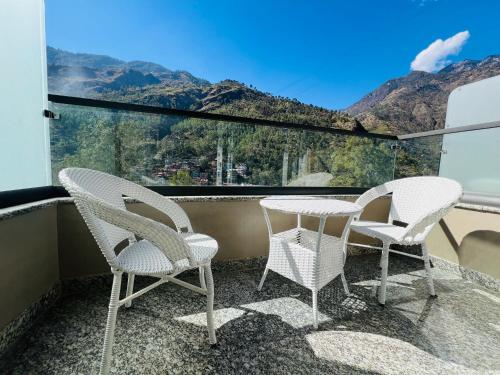 two chairs and a table on a balcony with mountains at Hotel Virasat-E-Bushahr in Rāmpur