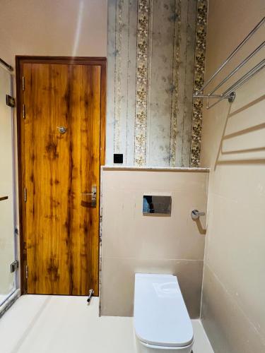 a bathroom with a toilet and a wooden door at Hotel Virasat-E-Bushahr in Rāmpur
