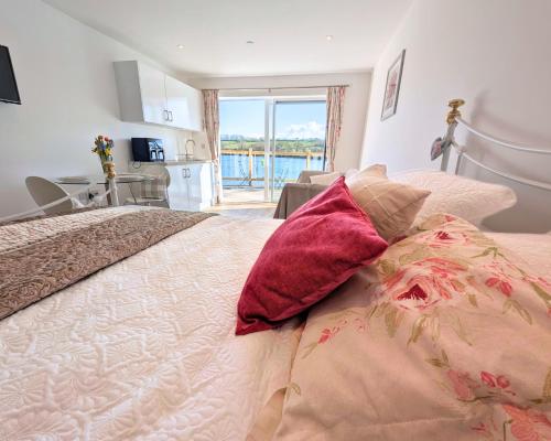 a bedroom with a bed and a kitchen with a window at Otter's Pool Studio Apartment at Galwad Y Mor in Saint Dogmaels