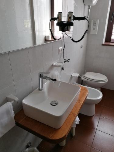a white bathroom with a sink and a toilet at Albergo Sella - Monte Amiata in Abbadia San Salvatore