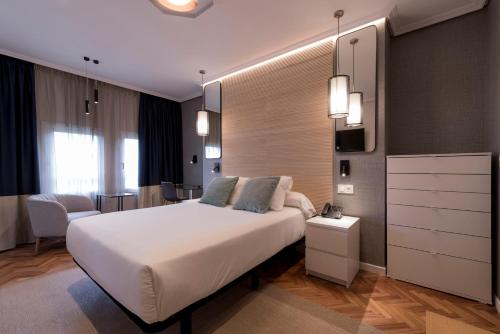 Un dormitorio con una gran cama blanca en una habitación. en Avenida Lofts, en A Coruña