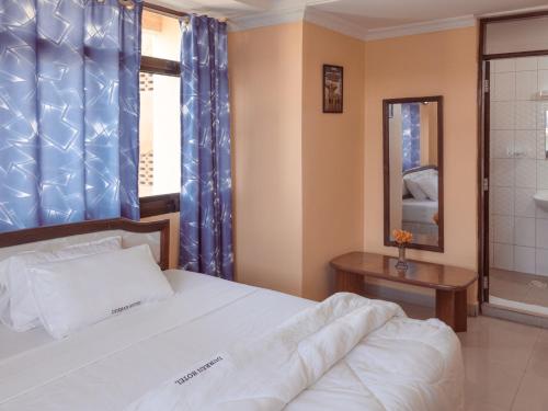 a bedroom with a bed and a window and a mirror at Durban Hotel in Dar es Salaam