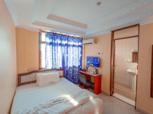 a bedroom with a bed and a desk and a sink at Durban Hotel in Dar es Salaam