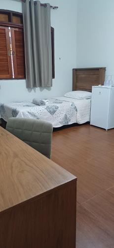 a living room with two beds and a table at Suíte privativa em casa de família - ENTRADA INDEPENDENTE - a tranquilidade - conforto e privacidade que vc procura - super limpinha com cozinha em BARÃO GERALDO- perto de tudo e sossego total in Campinas