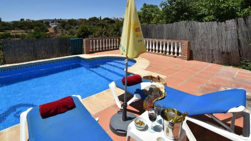 basen z 2 krzesłami i parasolem w obiekcie Villa La Lomilla w mieście Nerja