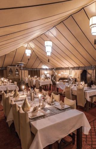 a dining room with white tables and chairs in a tent at Merzouga Sara Luxury Camp in Merzouga