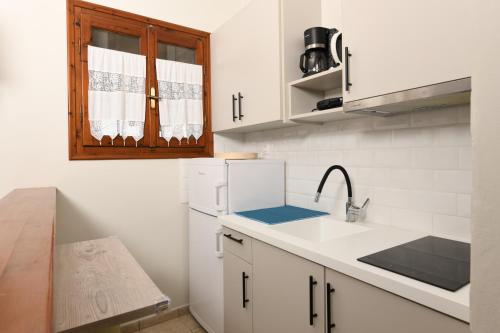 a kitchen with white cabinets and a sink and a window at Kotsoris Studios in Kyparissia