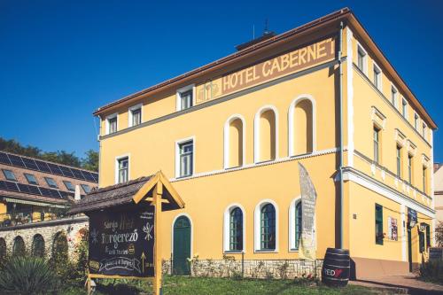 a yellow building with a sign in front of it at Hotel Cabernet in Villánykövesd