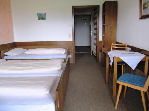 a room with two beds and a table and a chair at Erlebnislandgasthof Hotel Neiderhell in Kleinholzhausen